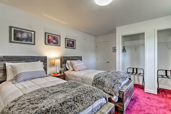 A bedroom with two beds, a nightstand, a lamp, and a closet with hanging clothes. - 'riversong' Waterfront La Crosse Home w/ Dock (La Crosse)