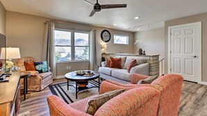 A spacious living room with a ceiling fan, a sofa, a coffee table, and a dining area with a lamp. - 'riversong' Waterfront La Crosse Home w/ Dock (La Crosse)