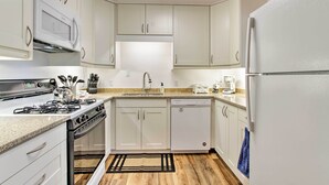 A modern kitchen with white cabinets, a gas stove, a dishwasher, and a refrigerator. - 'riversong' Waterfront La Crosse Home w/ Dock (La Crosse)