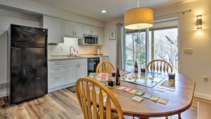 A modern kitchen with white cabinets, a black refrigerator, and a dining table with chairs. - 'riversong' Waterfront La Crosse Home w/ Dock (La Crosse)