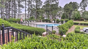 A swimming pool surrounded by a fence, with a brick wall and greenery in the foreground. - Resort-style Condo/suite on Golf Course w/ Pool! (Spring Lake)
