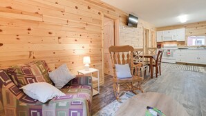 Un intérieur chaleureux, avec des murs en bois, un canapé, un fauteuil à bascule et une petite table à manger.