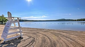A beach with a signboard titled "BEACH RULES" and a wooden chair. - Large Deck & Fire Pit: Secluded Pocono Lake Home (Pocono Lake)