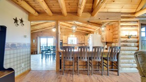 A wooden interior with a kitchen area, dining table, and chairs. - Rural New York Vacation Rental w/ Deck (Romulus)