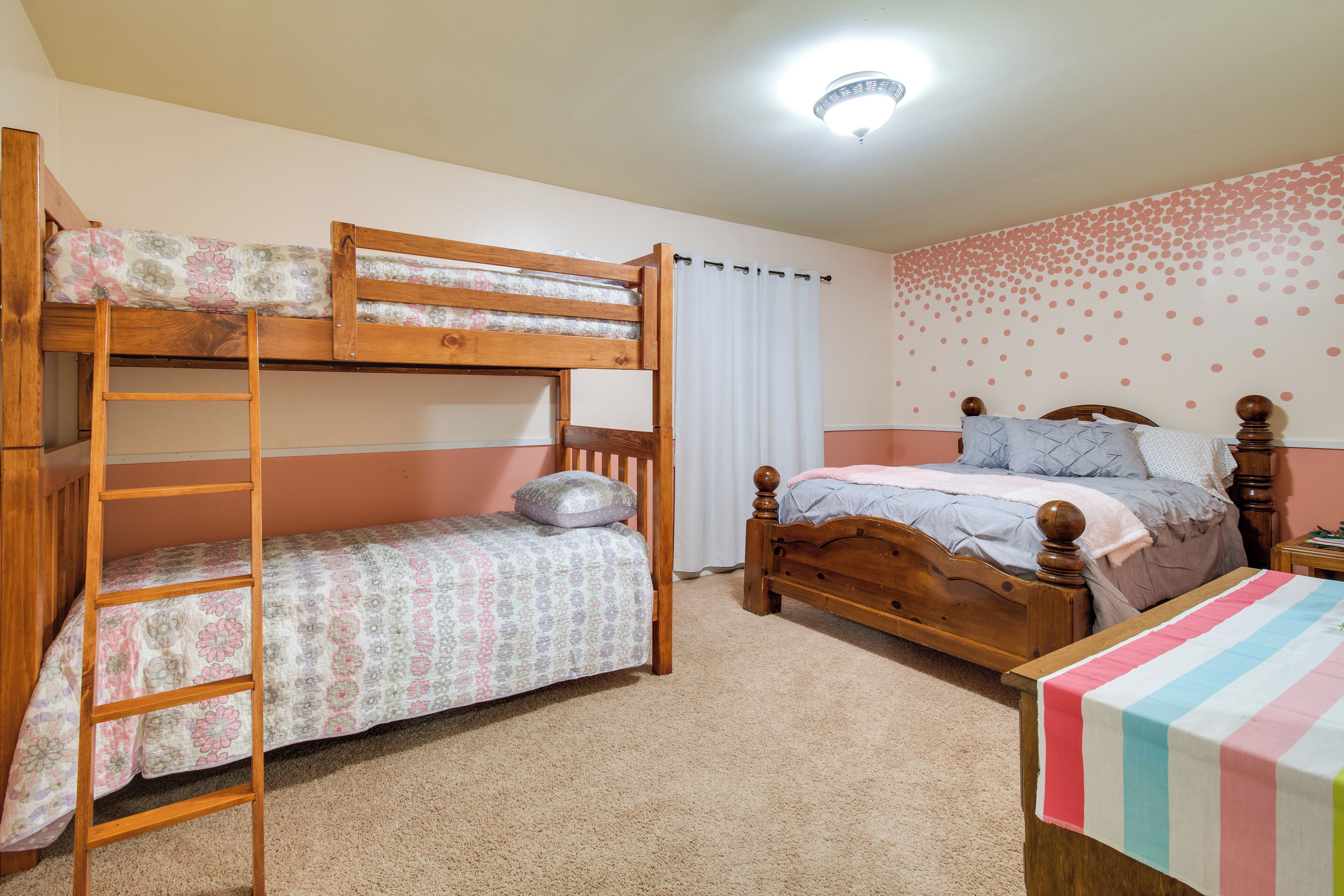 A bunk bed room with a ladder, a single bed, and a small table.