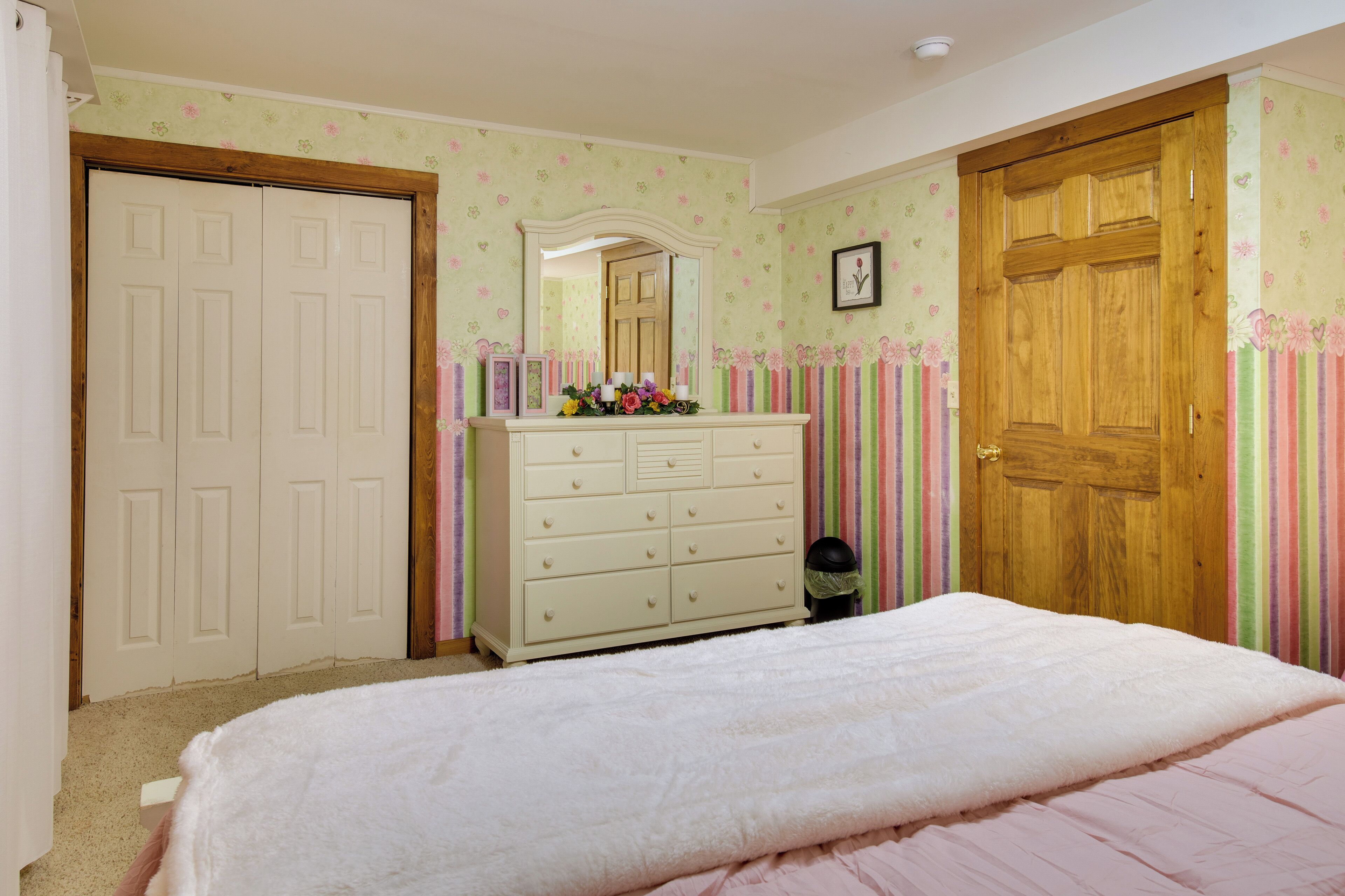 Un dormitorio con cama, cómoda, espejo y puerta.
