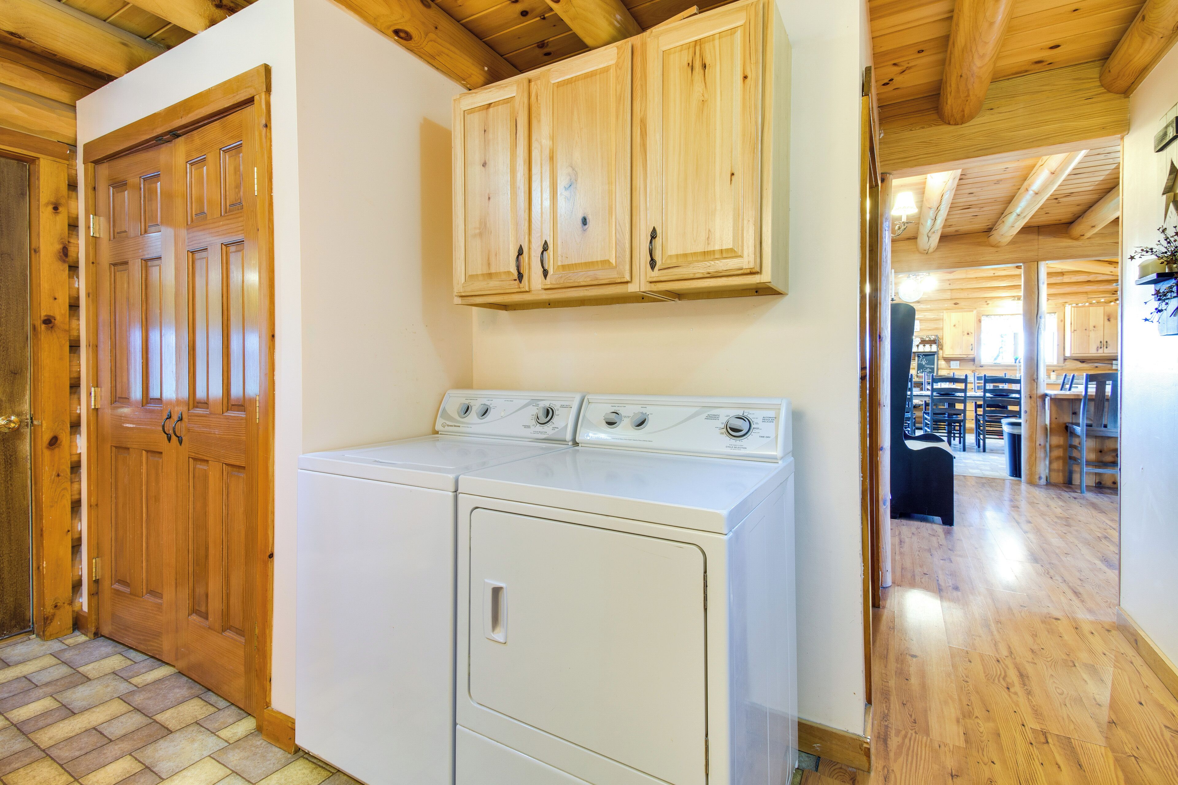 A laundry area with wooden cabinets and a front-loading washer and dryer.