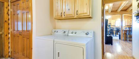 A laundry area with wooden cabinets and a front-loading washer and dryer.