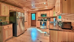 Cocina de cabaña de madera con refrigerador de acero inoxidable, microondas, horno y tostadora.