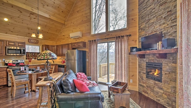 A cozy cabin interior with a wooden ceiling, stone fireplace, kitchen with modern appliances, and a comfortable seating area. - Hot Tub & Views: Charming Bryson City Cabin! (Bryson City)