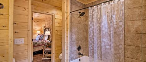 A wooden interior with a bathroom featuring a bathtub, shower curtain, and tiled walls.