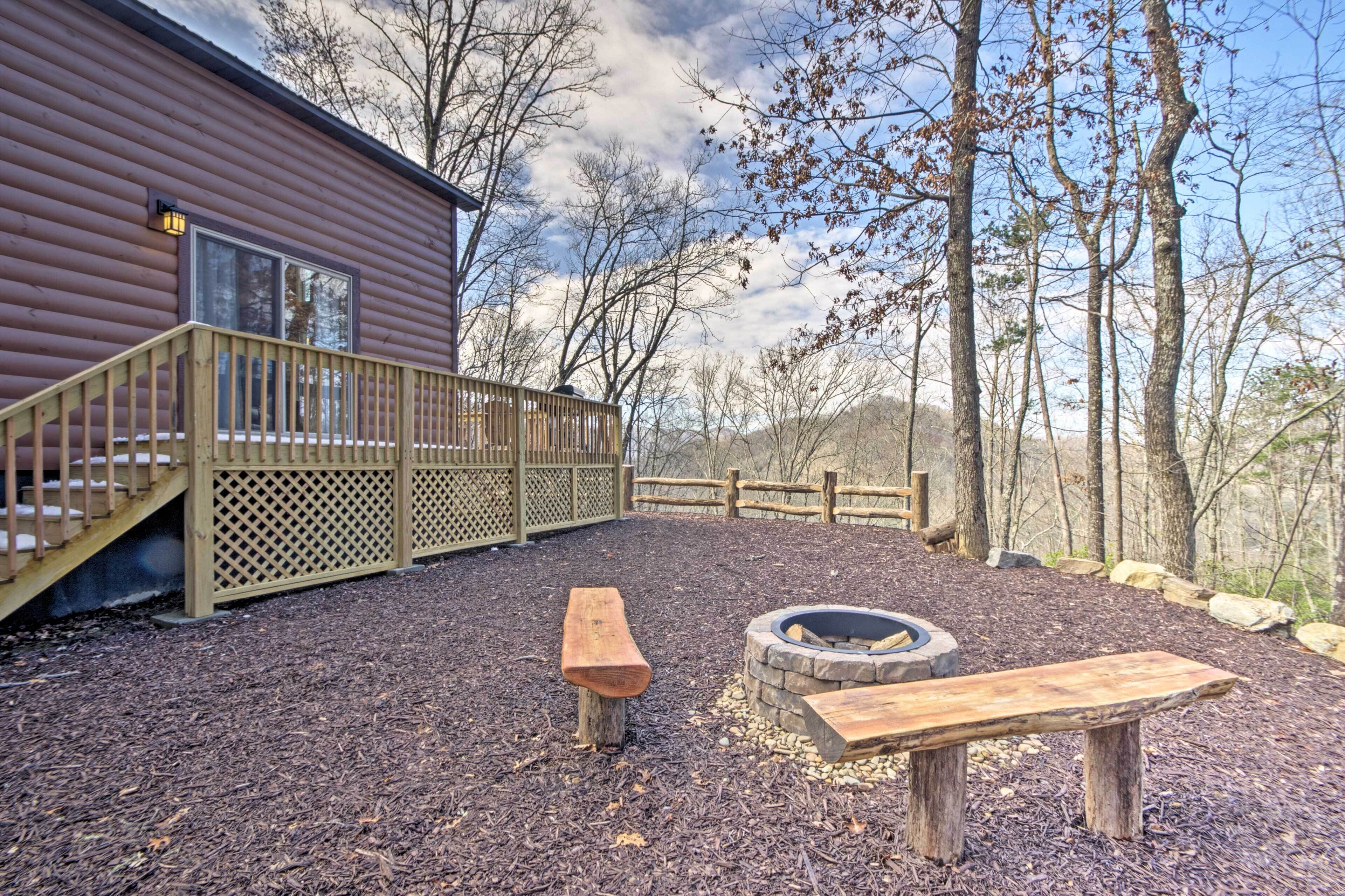 A cabin with a wooden deck, a fire pit, and a bench.