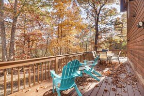 A wooden deck with two turquoise Adirondack chairs and a small table, surrounded by trees with autumn foliage. - Spacious Family Home w/ Deck at Massanutten Resort (McGaheysville)