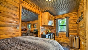 Un dormitorio de cabaña de madera con una cama, un escritorio y una ventana.