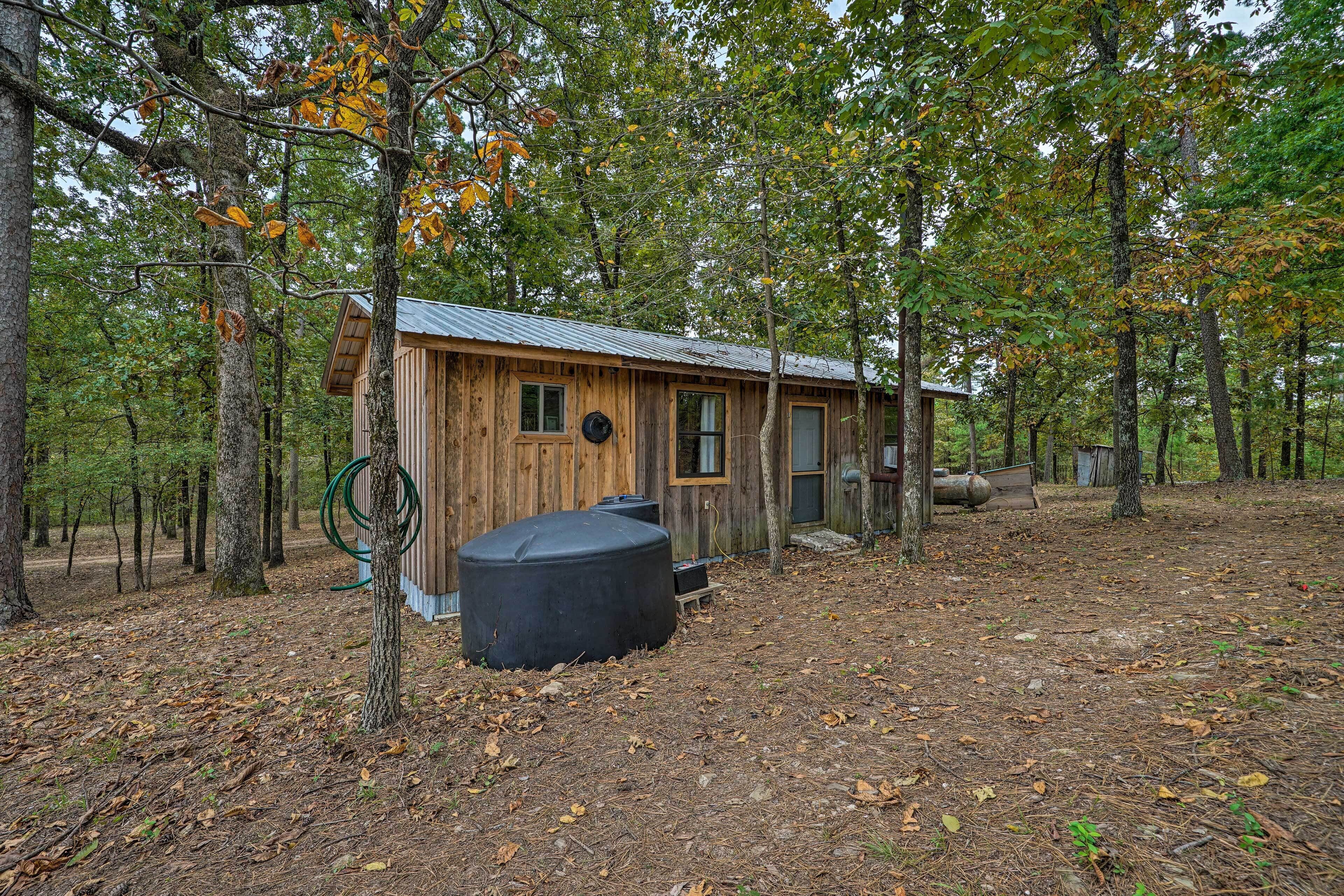 A rustic wooden cabin surrounded by trees in a wooded area.
