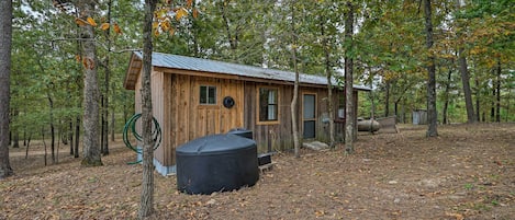 A rustic wooden cabin surrounded by trees in a wooded area.