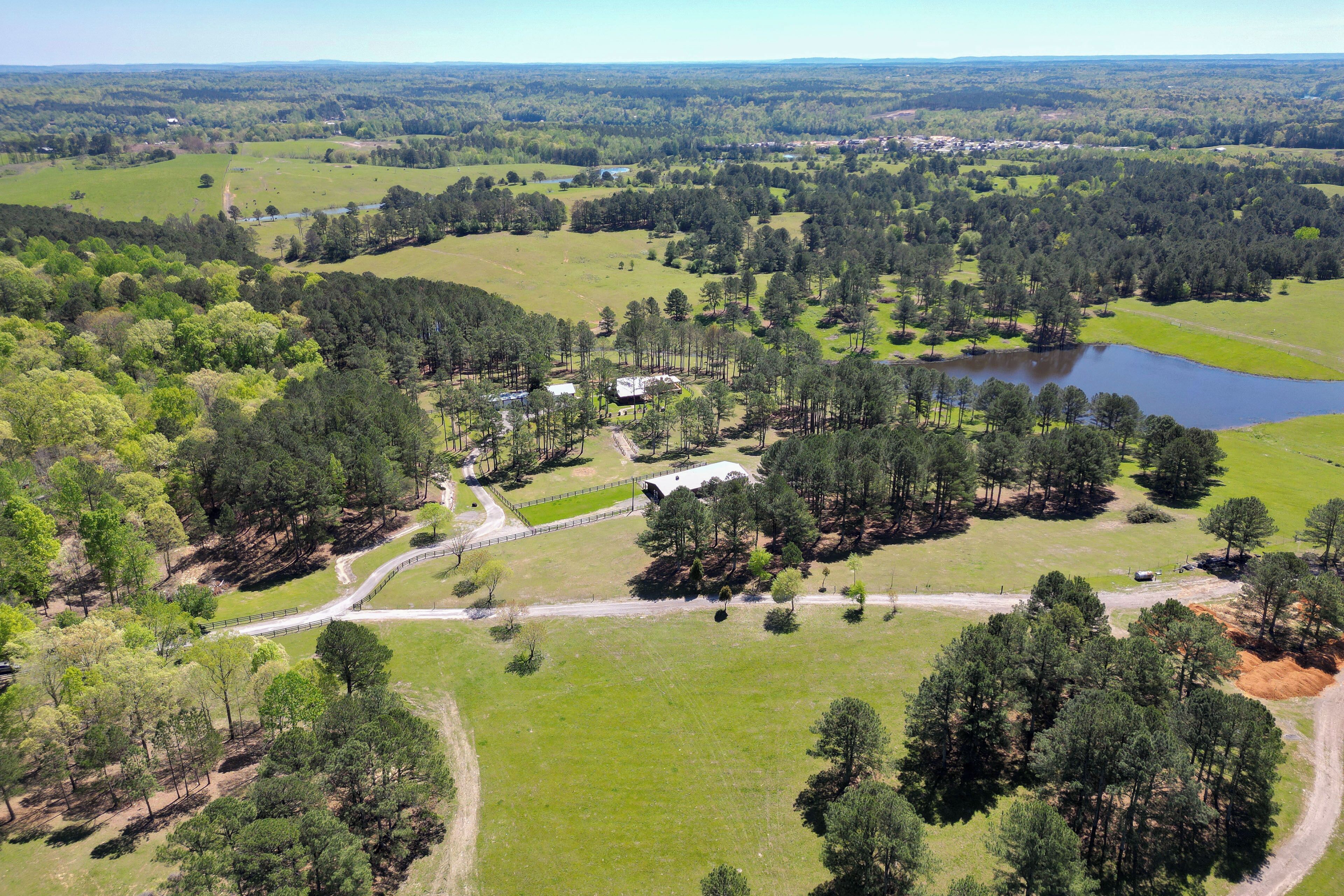 An aerial view of a rural property with open fields, a pond, and scattered trees.