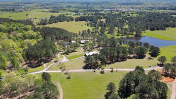 An aerial view of a rural property with open fields, a pond, and scattered trees.