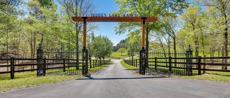A road leading to Hidden Lake Ranch with a wooden archway and black gates.