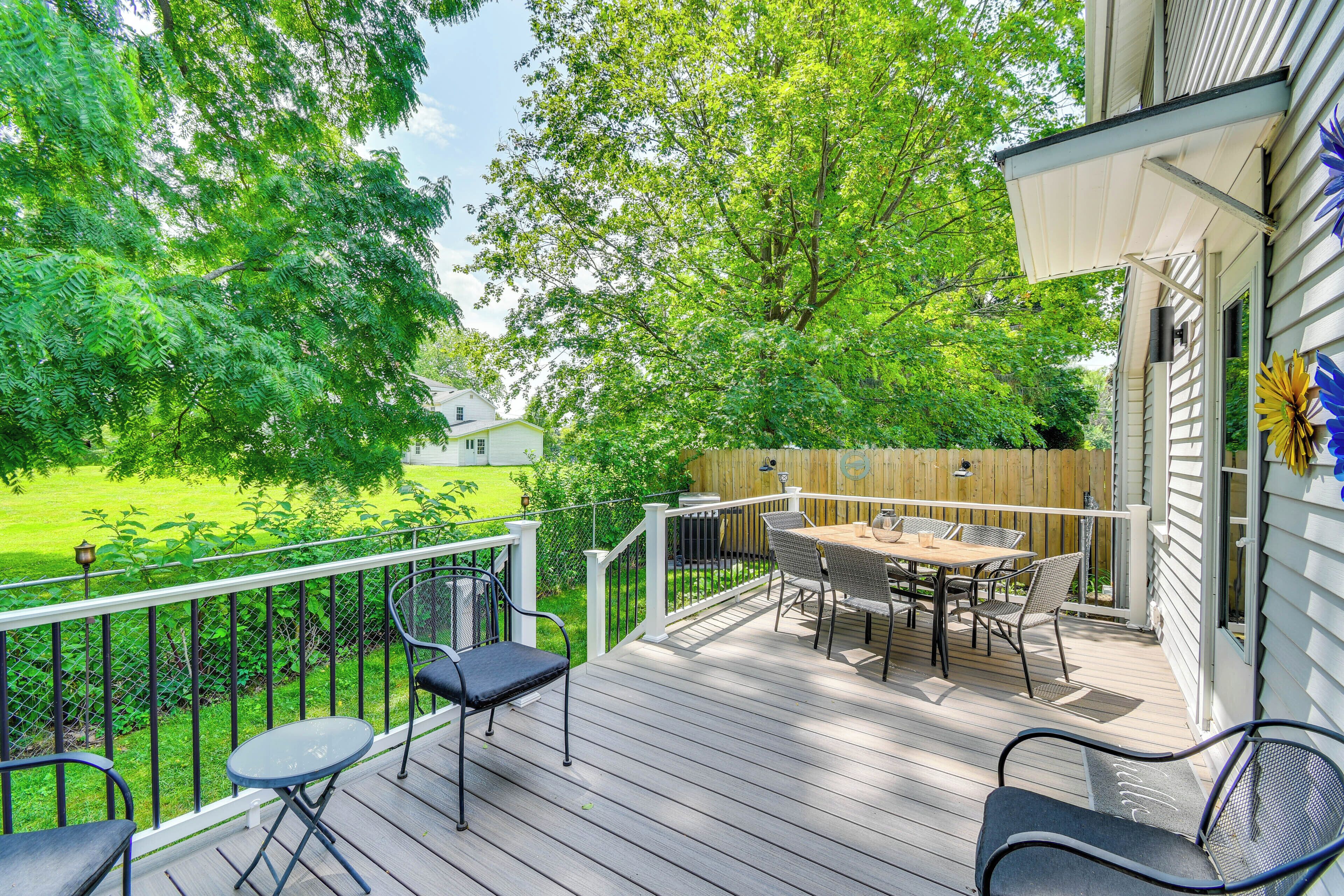 A wooden deck with outdoor furniture, a view of a green yard, and a wooden fence.