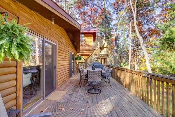 A wooden deck with outdoor furniture, a glass door entrance, and a view of trees.