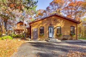 A wooden cabin with a porch, a small deck, and a bench.