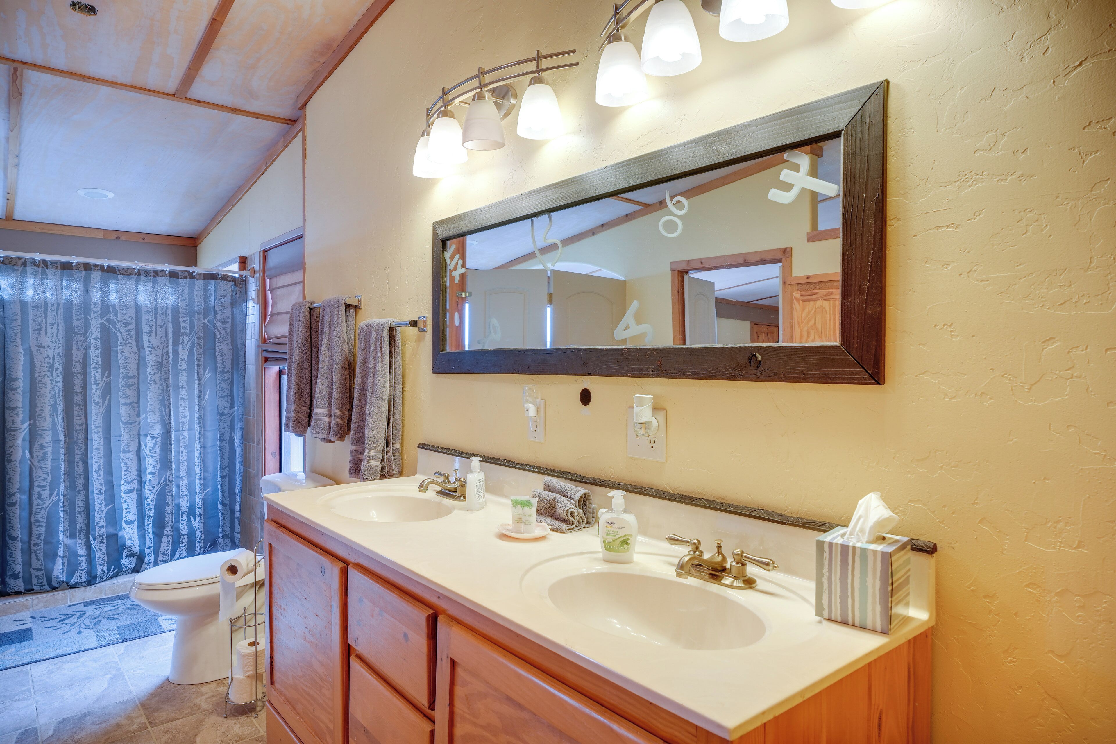 Un baño con dos lavamanos, un espejo grande y una cortina de ducha.