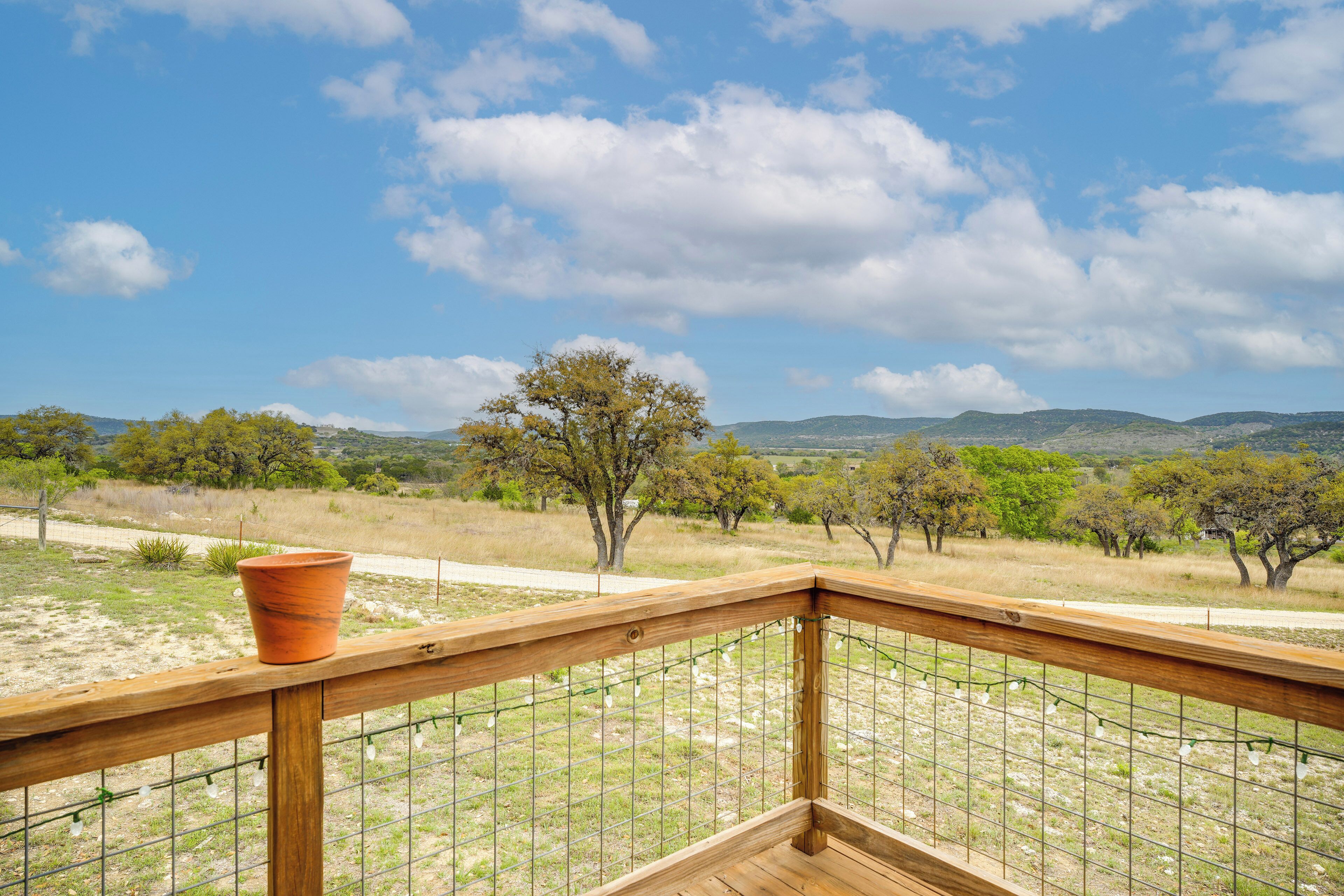 A wooden deck with a view of a grassy landscape and trees.
