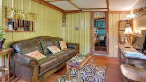 A cozy living room with a leather sofa, wooden coffee table, and a patterned rug. - Serene Green Forest Hideaway w/ Spacious Yard (Green Forest)