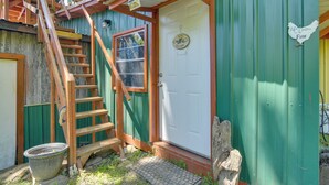 A rustic wooden staircase leading to a green door with a white sign that reads "Life's better on the farm." - Serene Green Forest Hideaway w/ Spacious Yard (Green Forest)