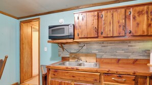 A kitchen with wooden cabinets, a microwave, and a sink. - Serene Green Forest Hideaway w/ Spacious Yard (Green Forest)
