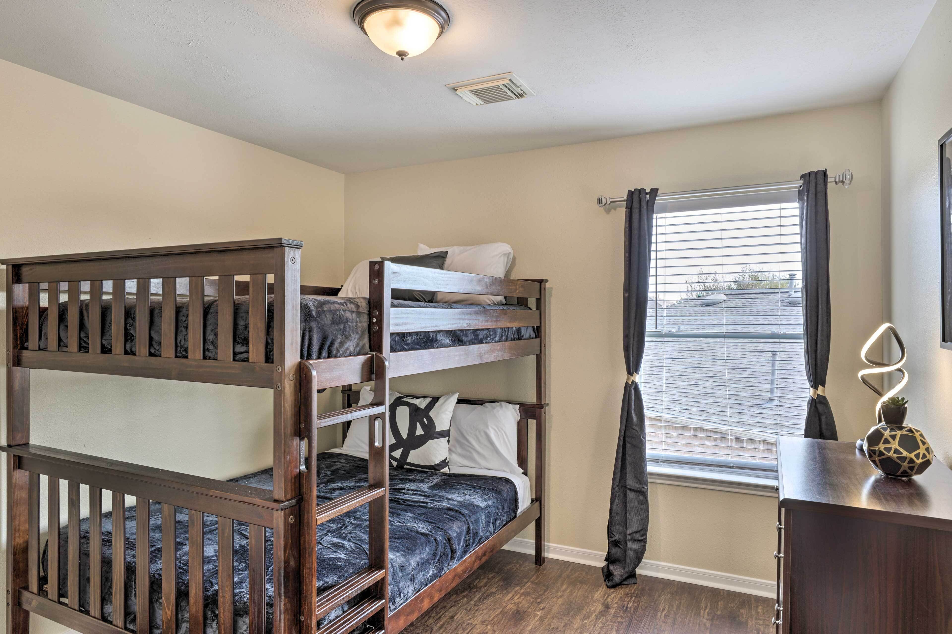 A bunk bed room with a window, a desk with a lamp, and a ceiling light.