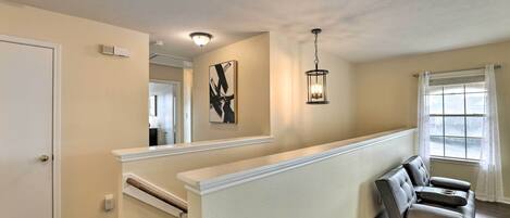 Een modern interieur met een neutraal kleurenpalet, een trap, een zithoek en een groot raam met uitzicht.