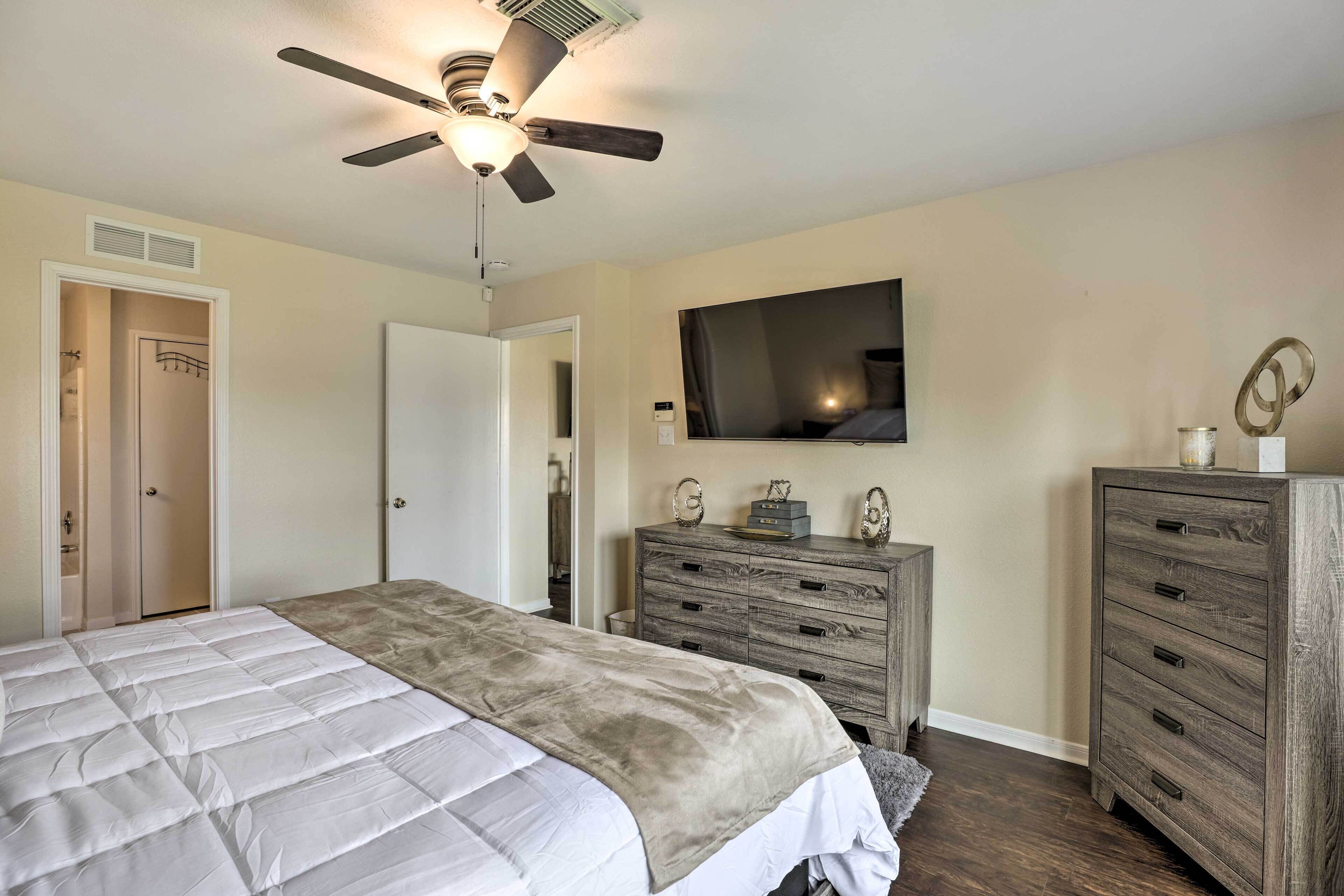 A bedroom with a bed, a dresser, a mirror, and a ceiling fan.