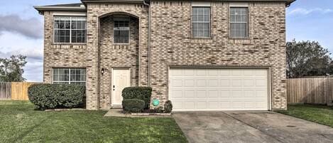 A two-story house with a brick exterior, a garage, and a well-maintained lawn.