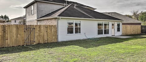 A single-story house with a fenced backyard, a covered patio, and a visible chimney.
