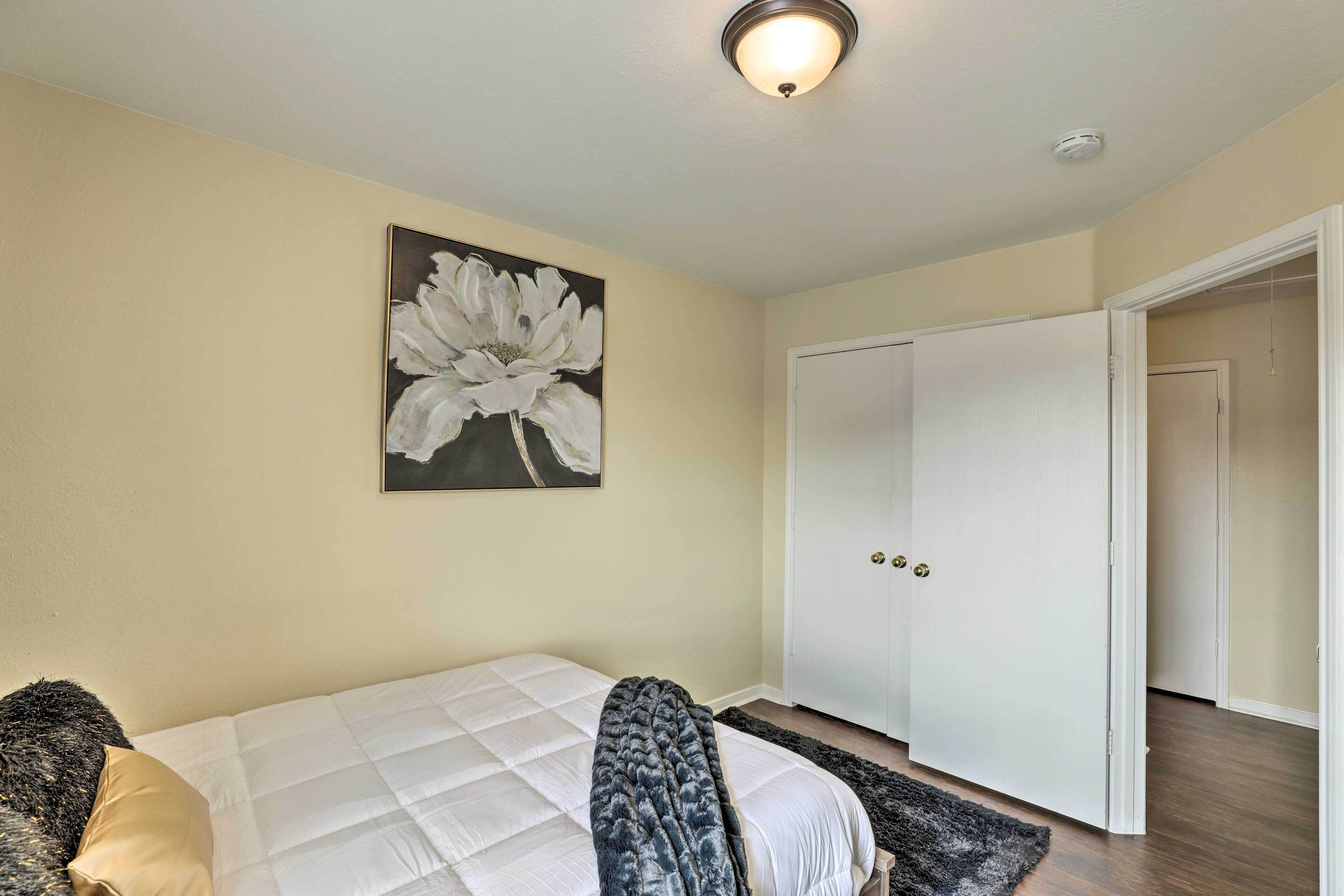 A bedroom with a bed, a painting, a wardrobe, and a door leading to another room.