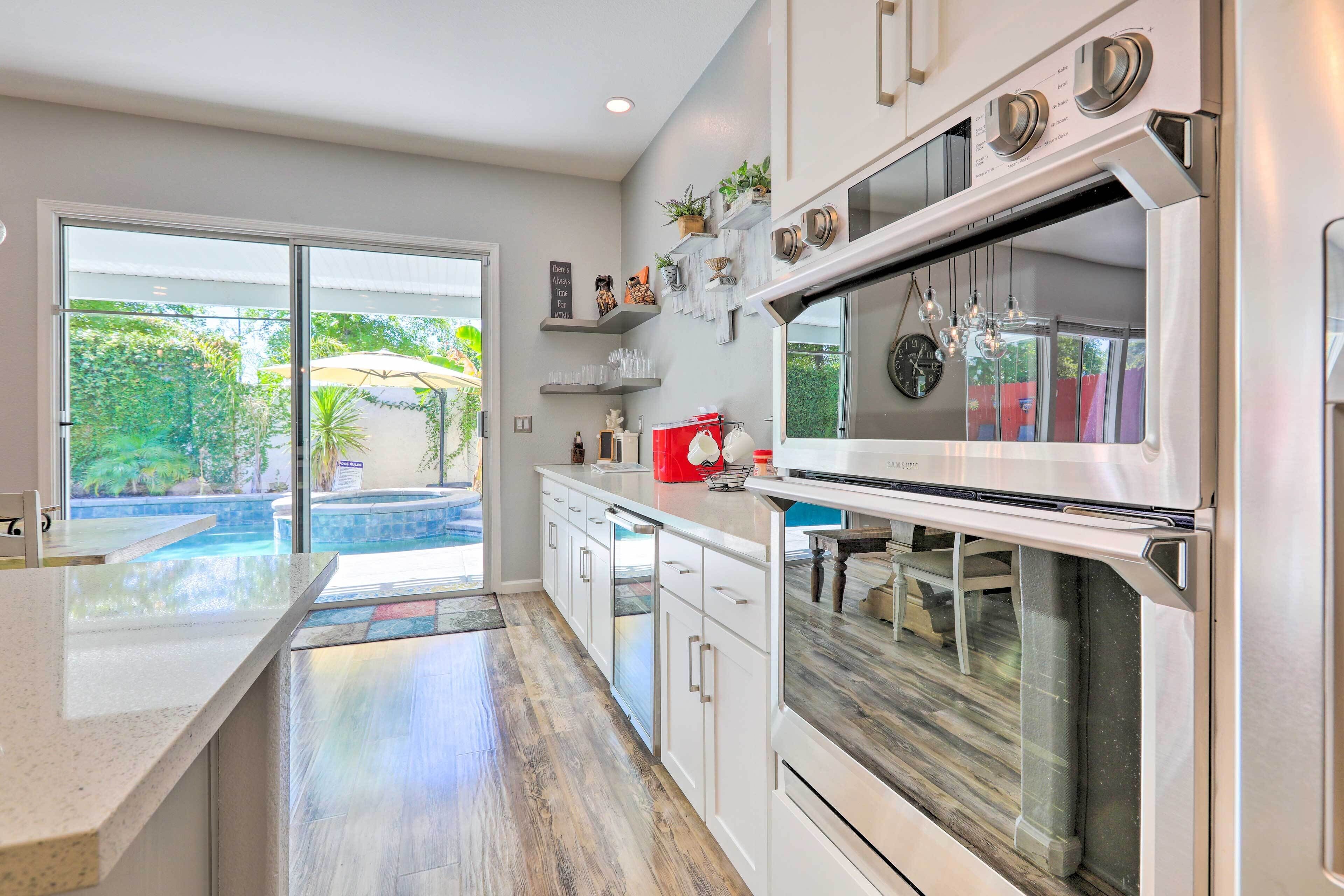 A modern kitchen with a large oven, white cabinets, and a view of a swimming pool.