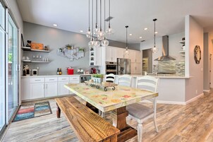 Una cocina moderna con armarios blancos, una isla central y un comedor con banco.