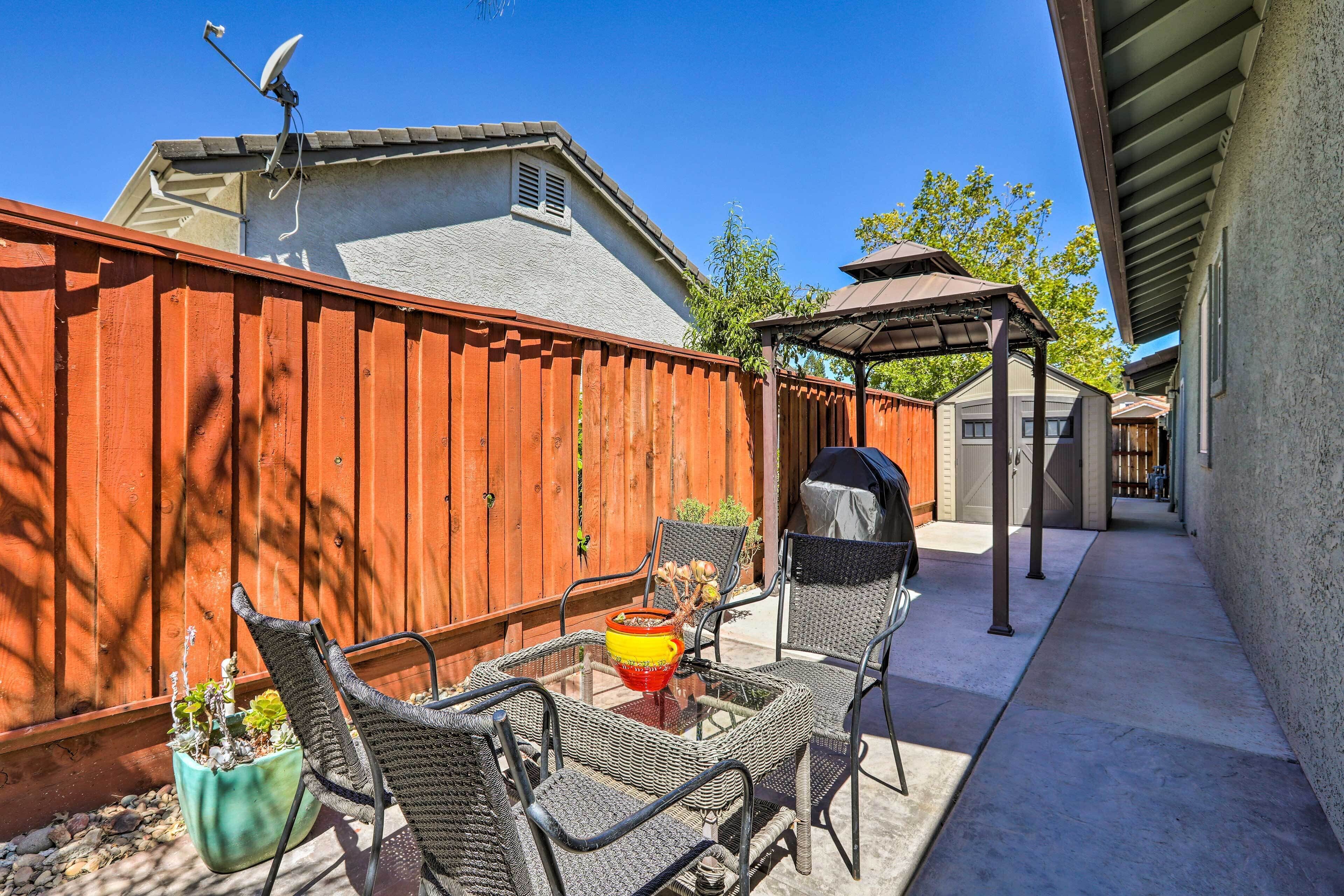 A patio with wicker chairs, a glass table, and a potted plant.
