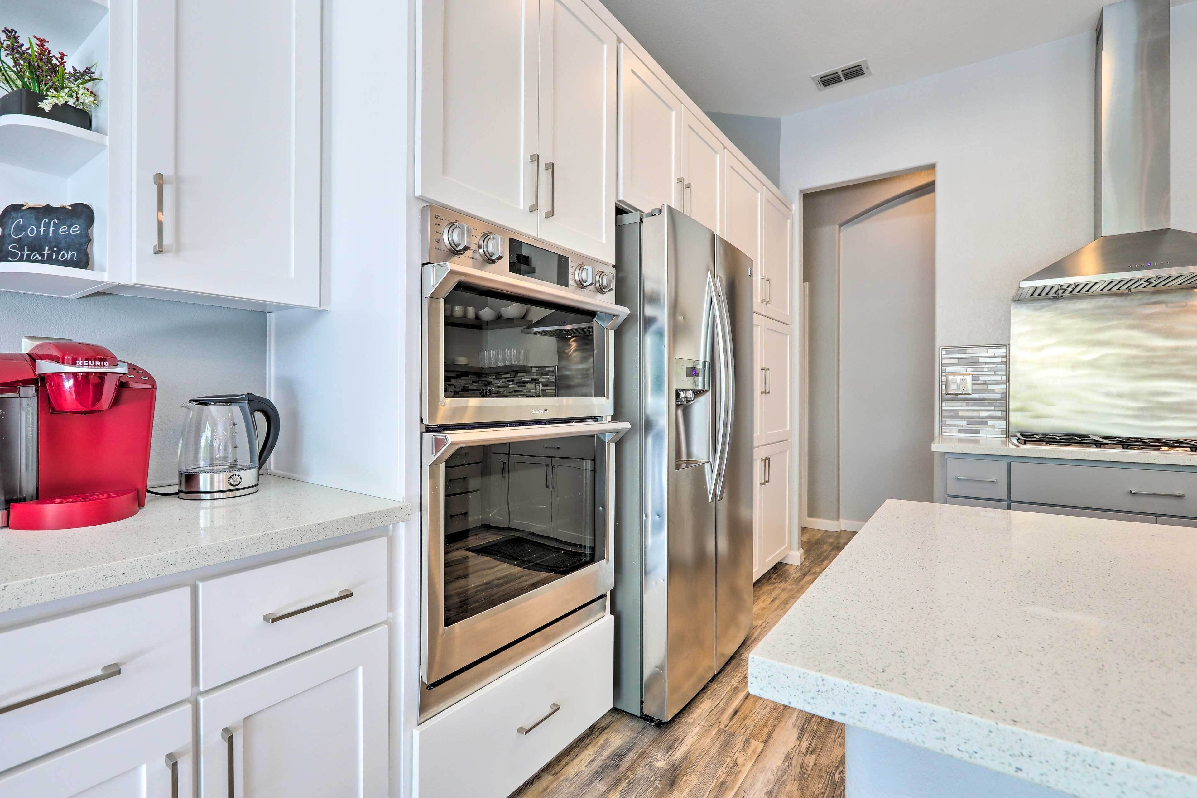 A modern kitchen with white cabinetry, a stainless steel oven, and a refrigerator.