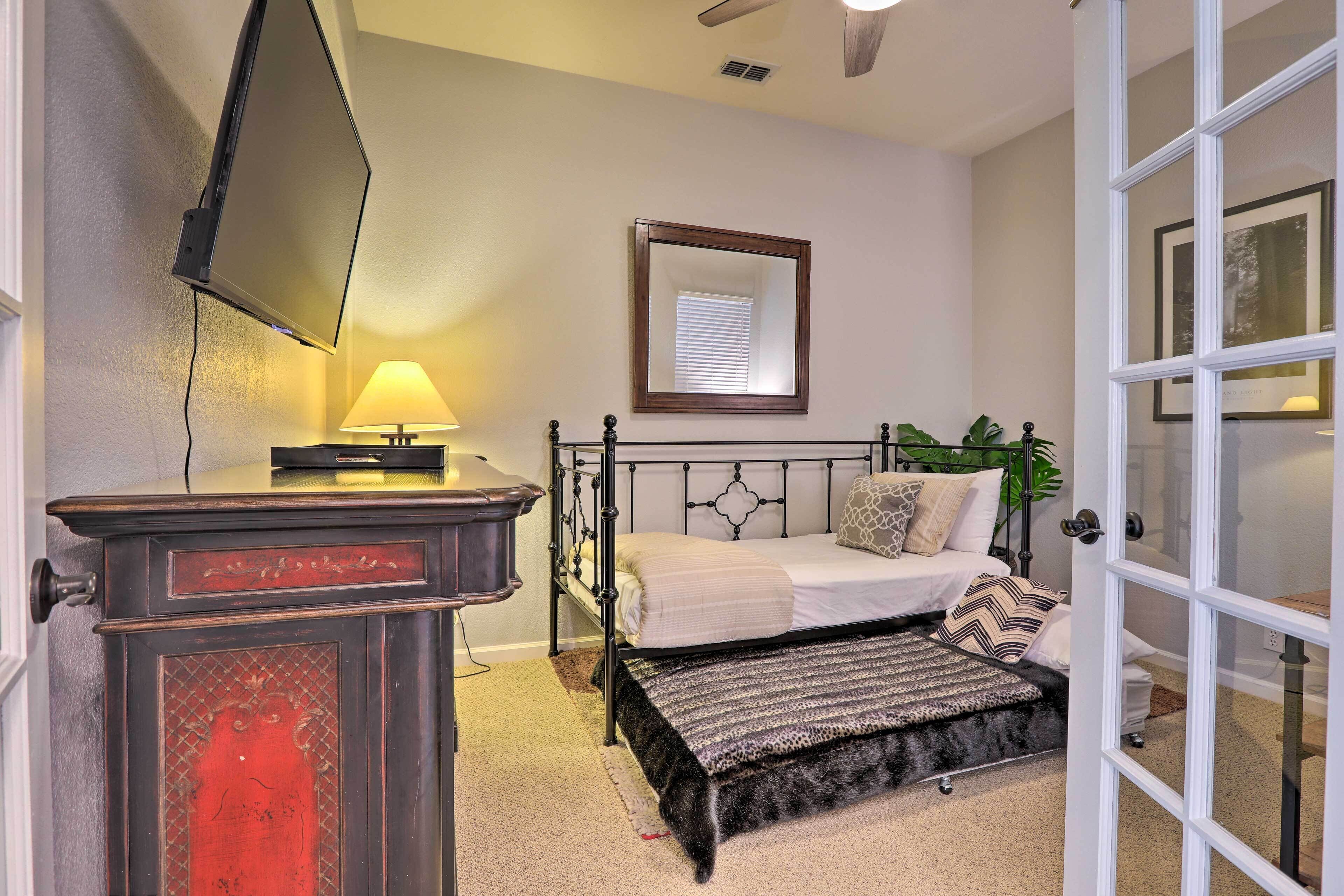 A bedroom with a bed, bedside table, lamp, mirror, and a door.
