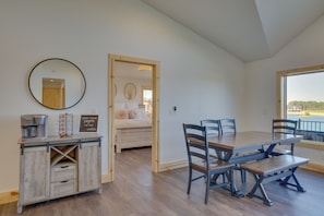 Un comedor con mesa y sillas de madera, una estación de café y vistas al exterior.