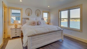 A bedroom with a large bed, two bedside tables, and a view of a body of water through a large window. - Lakefront Luxury - 1 MI to Buckhorn Boat Landing (New Lisbon)