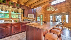 A spacious kitchen with wooden cabinets, a large island, and bar stools.