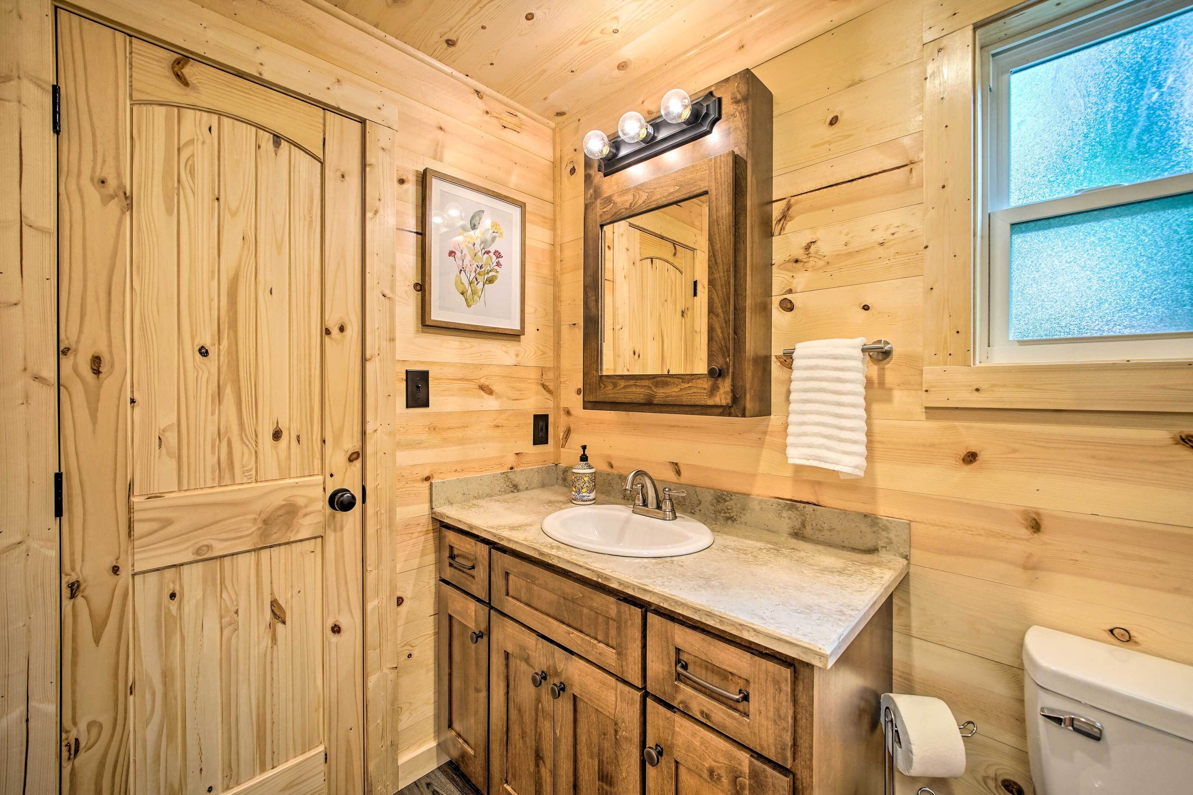A wooden bathroom with a sink, mirror, and toilet.
