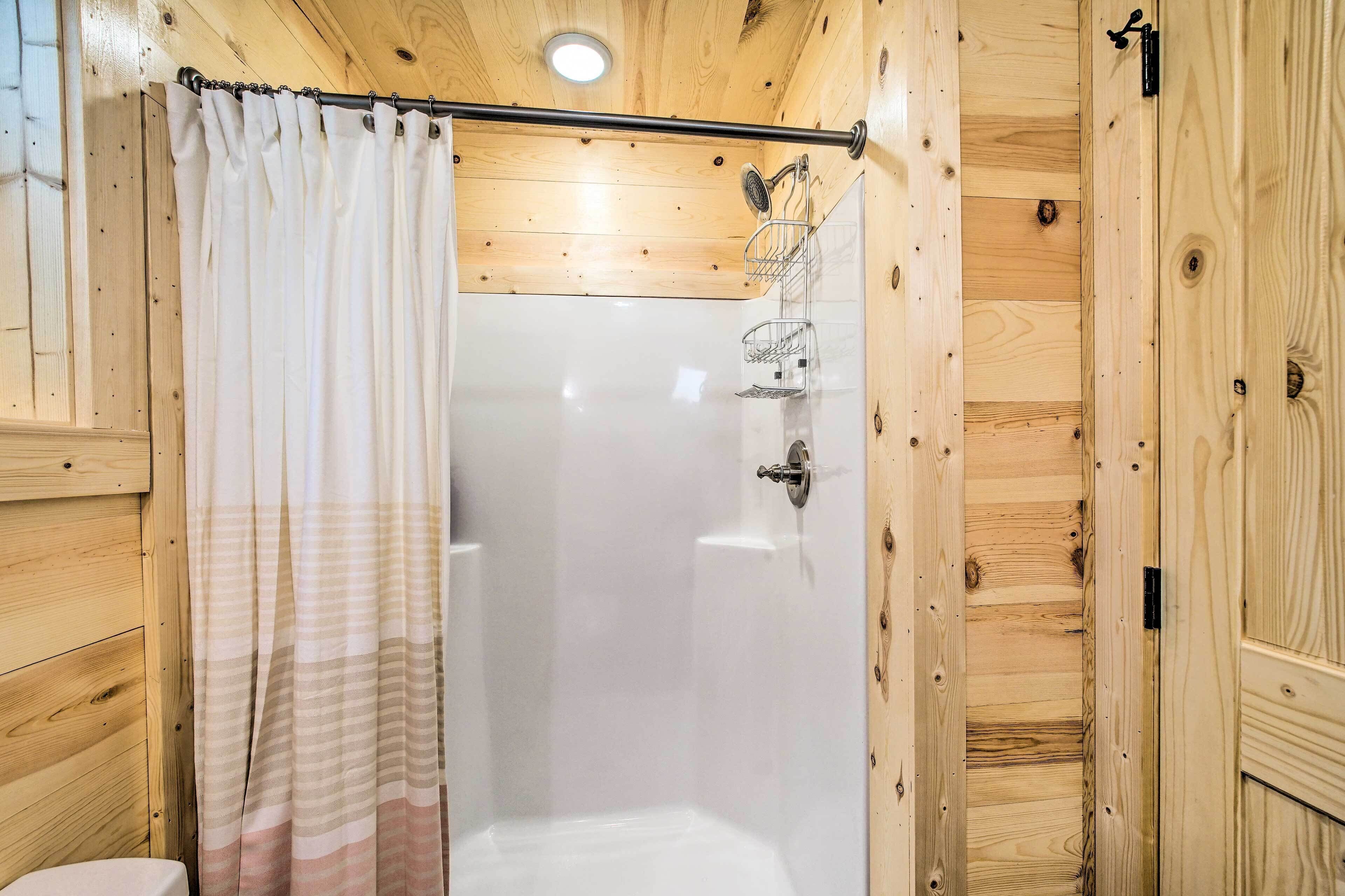 A wooden cabin bathroom with a shower, a toilet, and a towel rack.