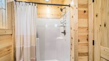 A wooden cabin bathroom with a shower, a toilet, and a towel rack.