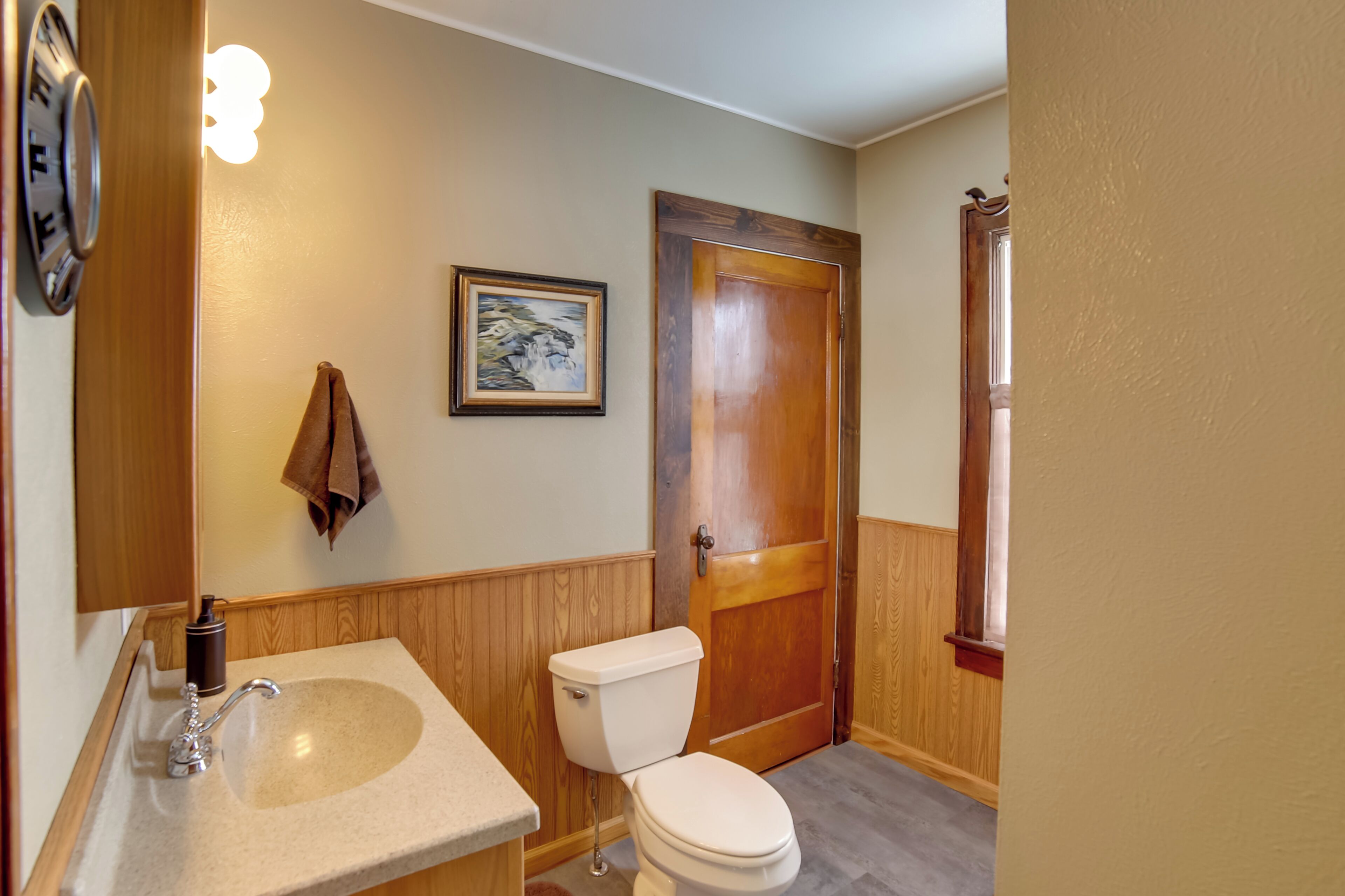 A bathroom with a wooden door, a sink, and a toilet.