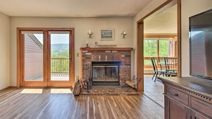 A spacious room with a fireplace, wooden flooring, and a large sliding glass door leading to a balcony. - Timber Creek Townhome w/ 2 Decks & Mtn Views! (West Dover)